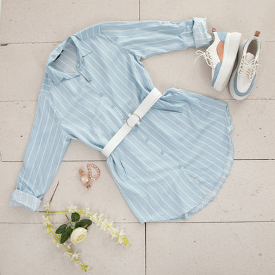 Light blue striped Shirt laid out  on the floor with a belt and shoes 