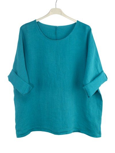 Teal oversized linen top on a hanger against a white background