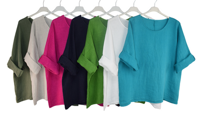 Set of colorful tops on hangers against a white background